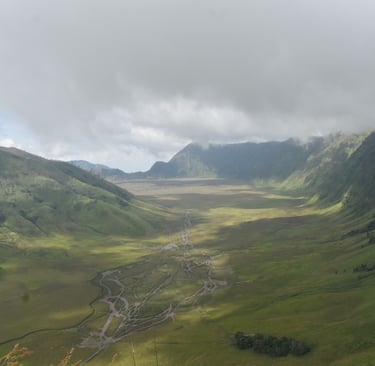 A photographer takes pictures of the green valley, the road leading to Mount Bromo