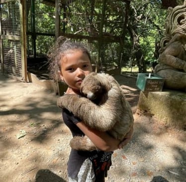 A little girl holding a sloth