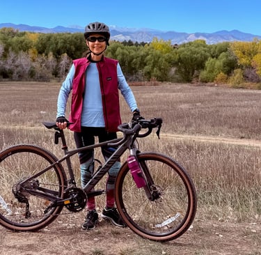 The author posing with her Canyon gravel bike against a distant mountain range backdrop