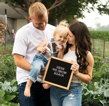 couple holding toddler announcing 2nd pregnancy