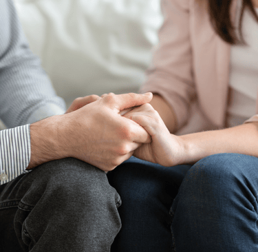 Couple holding hands and discussing fertility challenges