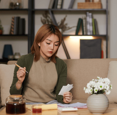 Woman calculating IVF costs at home with documents and calculator
