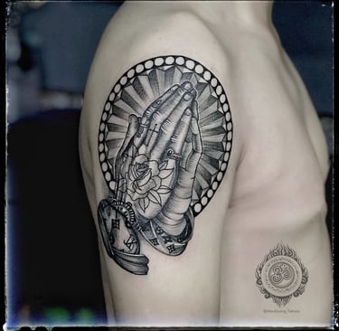 Blackwork tattoo of a praying hand with a rose tattoo on the upper arm