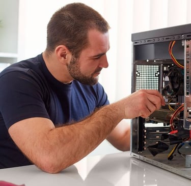 Professional technician repairing a desktop computer tower on a white desk in an office setting.
