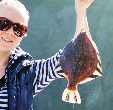 a woman holding a fish on a fishing boat