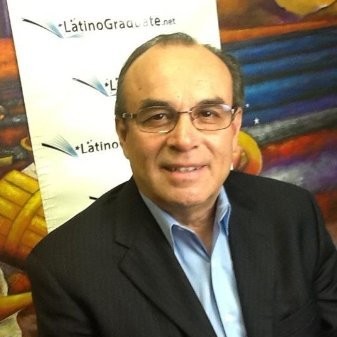 Head and shoulder image of a balding middle-aged man in a dark jacket, blue shirt, and spectacles