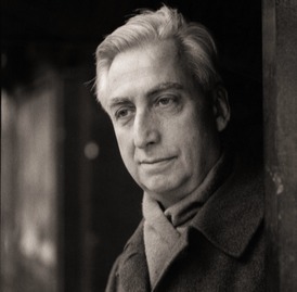 Black and white photograph of an elderly man with grey hair and wearing scarf tucked inside his jacket