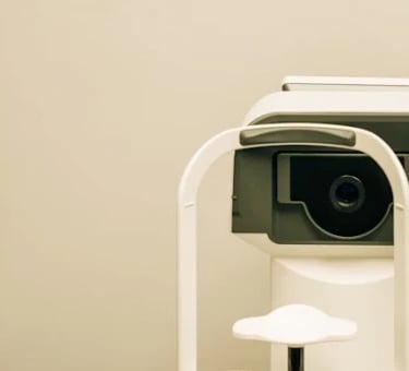 Optometry machine situated on an examination table, used for eye testing, in a clinical setting.