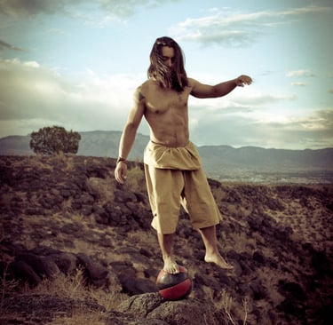 Joshua Fabia posing for a picture on a medicine ball in the Petroglyphs of New Mexico