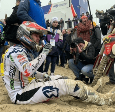 a man sitting on a dirt bike in the sand