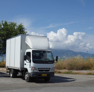 A white Luton type van is shown with a backdrop of the sea