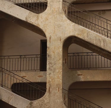 Concrete staircase with ornate wrought iron railings in an industrial building courtyard.