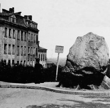 Vintage black and white photo of a large commemorative boulder monument in a European city plaza.