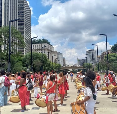 a group of people in red dresses and hats are playing drums