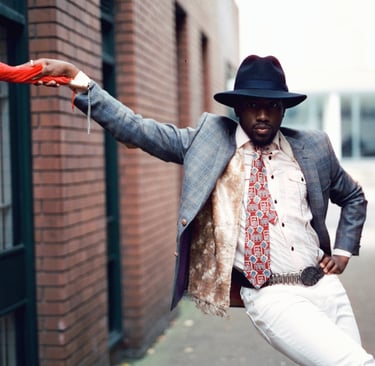 a man in a suit and hat holding a red umbrella