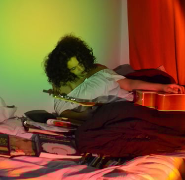 a woman sitting on a bed with a guitar