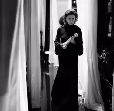 a woman in a black dress standing in front of a door