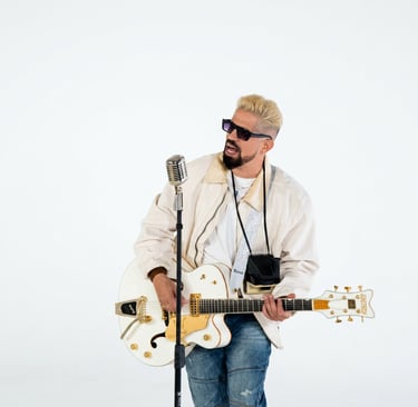 Musician with blonde hair playing a white Gretsch electric guitar and singing into a vintage microphone.
