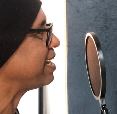 a man in a beanie hat and sunglasses is looking at a microphone