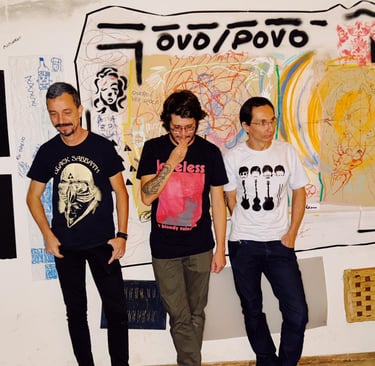 Indie rock band members in graphic t-shirts posing against a graffiti art wall in a music studio.