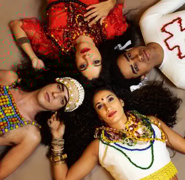 Four people in traditional Indian jewelry and colorful attire lying in a circle for a cultural portrait.