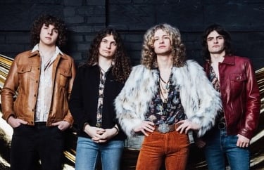 A 1970s style rock band with long hair wearing leather jackets and a faux fur coat.
