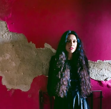 a woman in a black dress standing in front of a pink wall