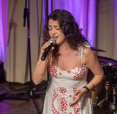 a woman in a white dress singing into a microphone