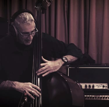 Professional musician playing a double bass in a recording studio with vintage amplifiers.