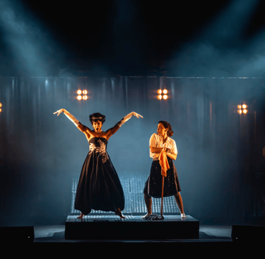 two women in black dresses standing on stage
