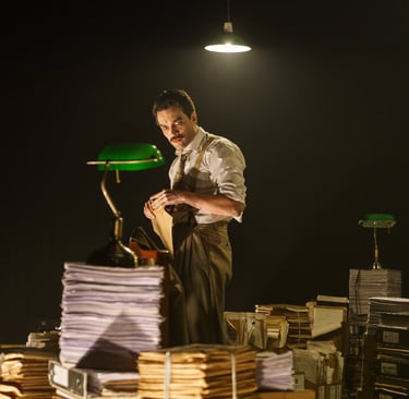 a man standing in front of a pile of papers