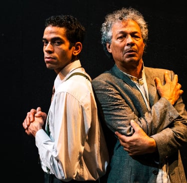 two men standing next to each other in a dark room
