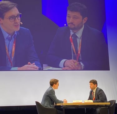 Two business professionals having a panel discussion on stage at a corporate conference event.