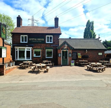 a restaurant with tables and benches in front of a brick building
