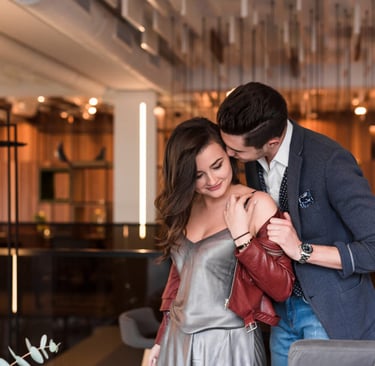 A sugar mommy in an elegant dress embracing her sugar baby in a luxurious restaurant.