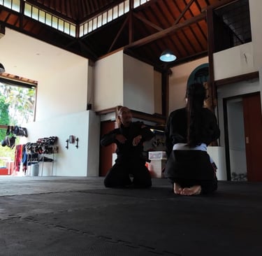 Adeline en kimono sur le tatami à Ubud, écoutant les explications de son professeur de Jiu-Jitsu bré