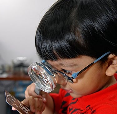 child reading through lens
