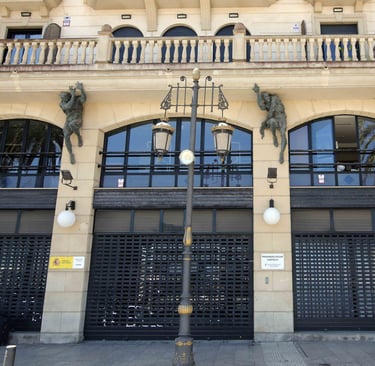 Ornate street lamp in front of a historic building with architectural statues and closed security shutters.