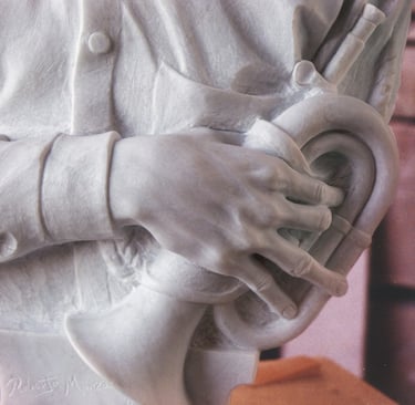 Hand-carved white marble bust of a young man holding a bugle in a workshop setting.