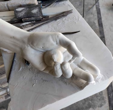 Detailed marble sculpture of a hand holding a small sphere on a stone workbench with carving tools.