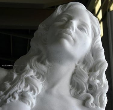 A classical white marble sculpture of a nude woman standing in an artist workshop.