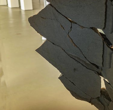 A sculpture of a block of stone broken into pieces and reconstructed like a puzzle in an exhibition