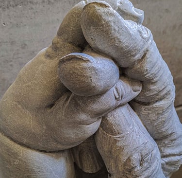 A marble sculpture of a child's hand embracing the relaxed hand of an elderly person