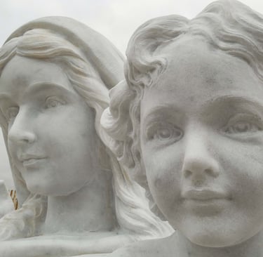 Close-up of a white marble religious statue depicting a woman and child with serene expressions.
