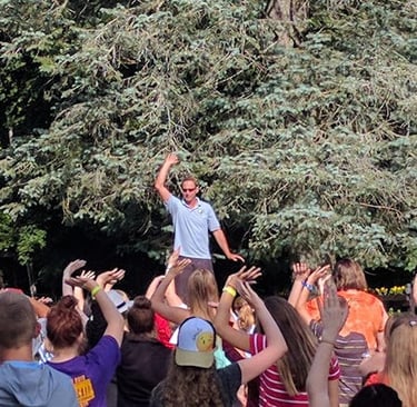 Johnny teaching children Tai Chi outdoors on a picnic table at Make Arthritis Stop Hurting Camp