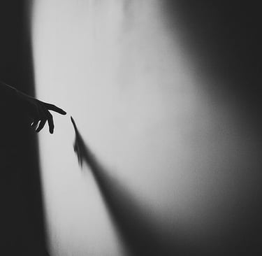 black and white photo hand on wall casting shadow