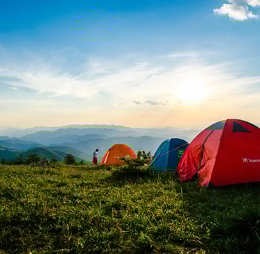 um grupo de tendas de acampamento montadas em uma colina gramada
