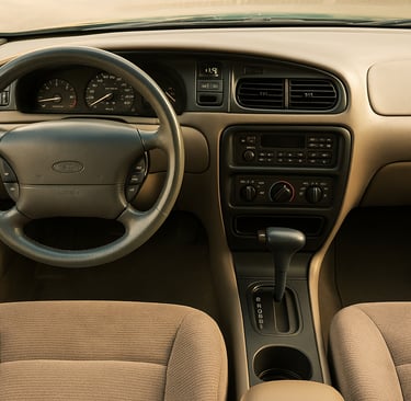 Interior do Ford Taurus 1995 com volante original, painel digital e câmbio automático, iluminação na