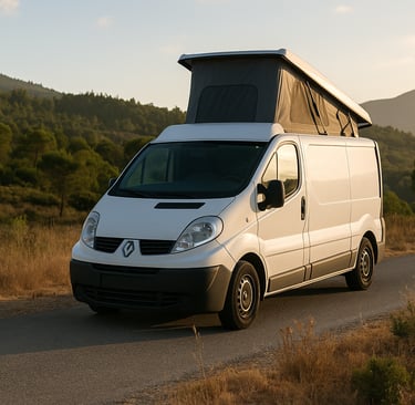 Van Renault Master usada adaptada como camper estacionada em estrada com montanhas ao fundo