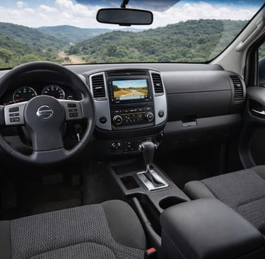 Interior da Nissan Frontier com painel, volante, central multimídia e câmbio automático, vista a par